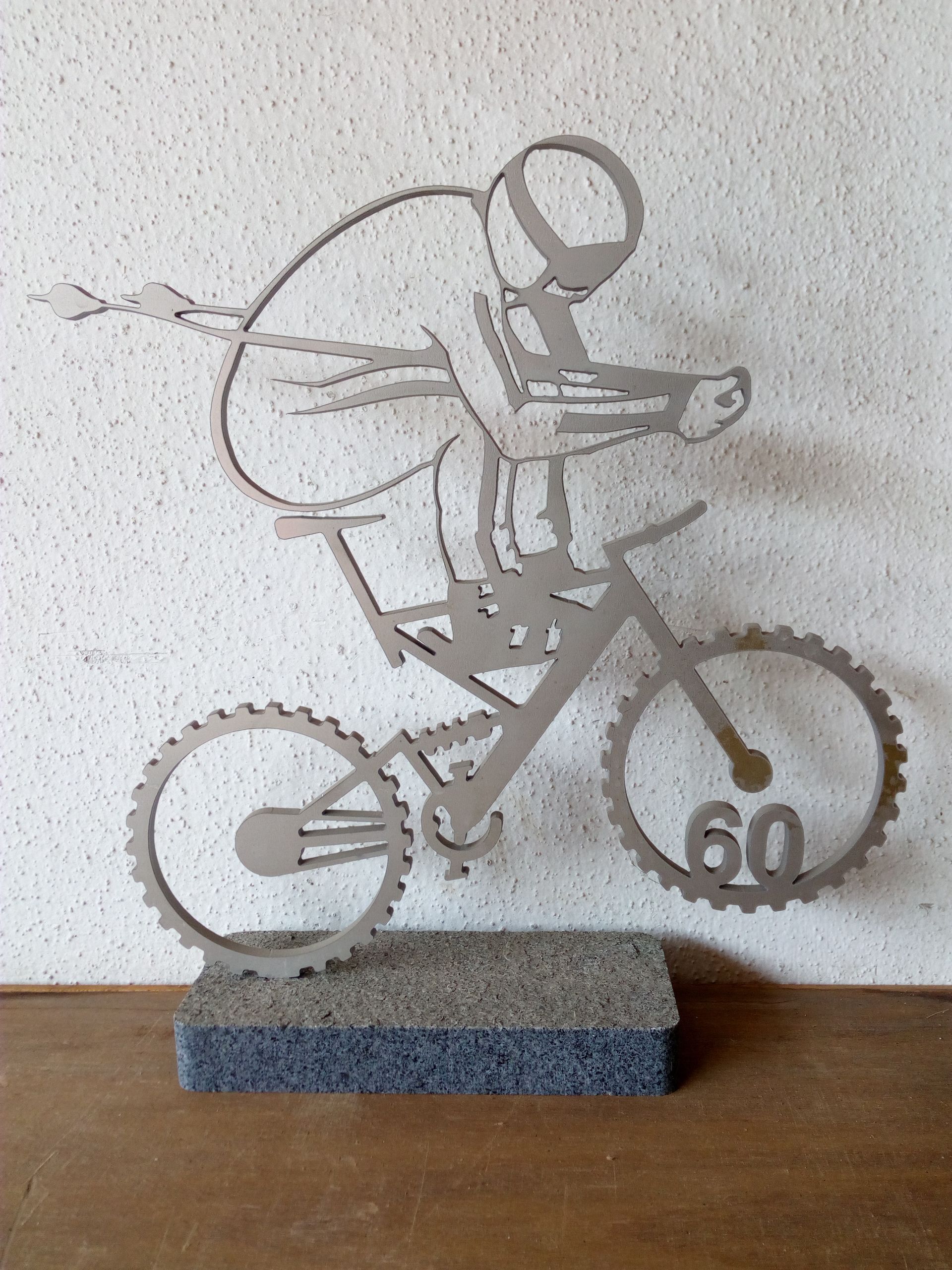 Eine Metallskulptur einer Person auf einem Fahrrad mit der Nummer 60 auf dem Vorderrad