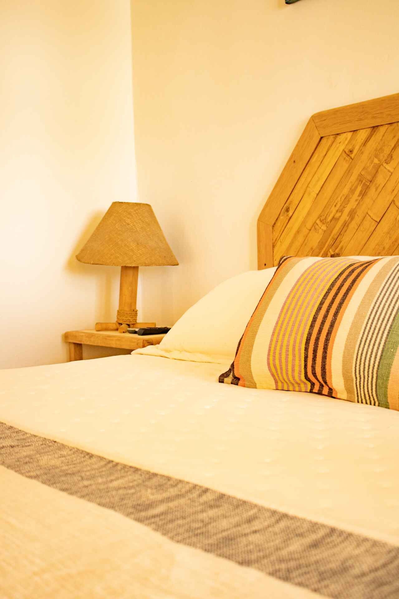Bedroom with wooden headboard, bedside lamp, and striped pillow.
