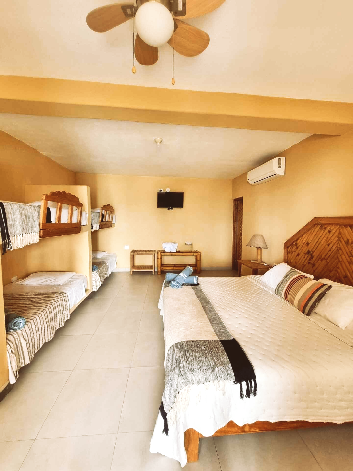A hotel room with three beds and a ceiling fan