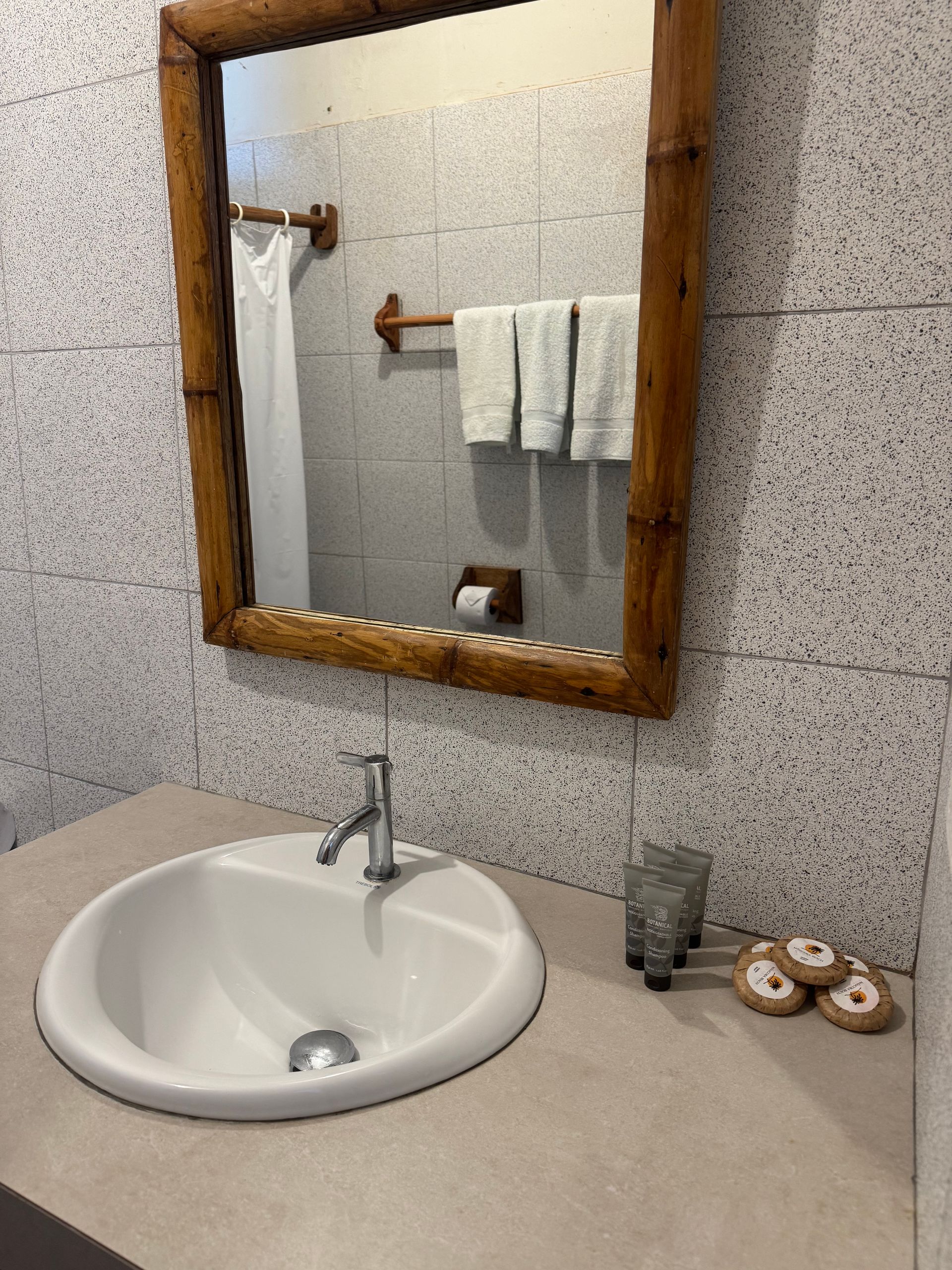 Bathroom with a white sink, mirror with a bamboo frame, and towels.