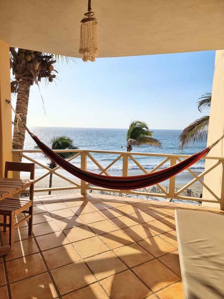 A hammock is hanging on a balcony overlooking the ocean.