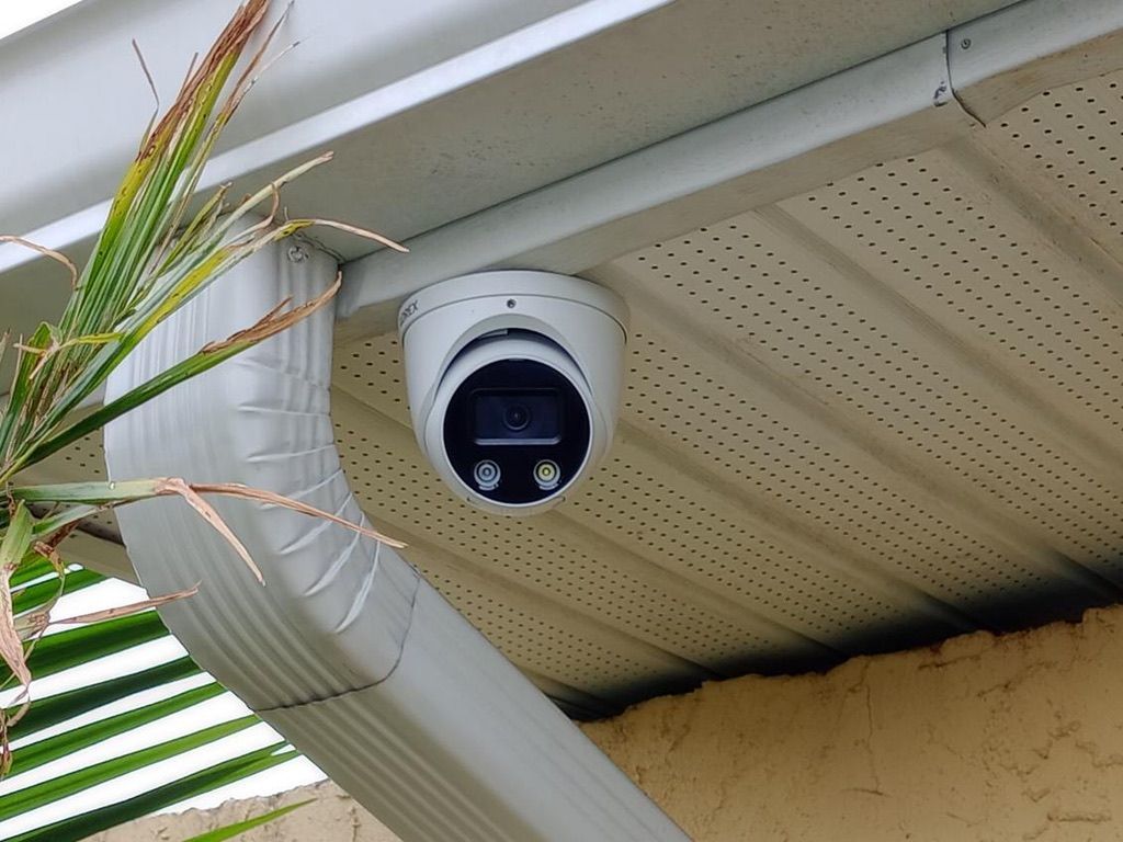 A security camera is mounted on the roof of a house.