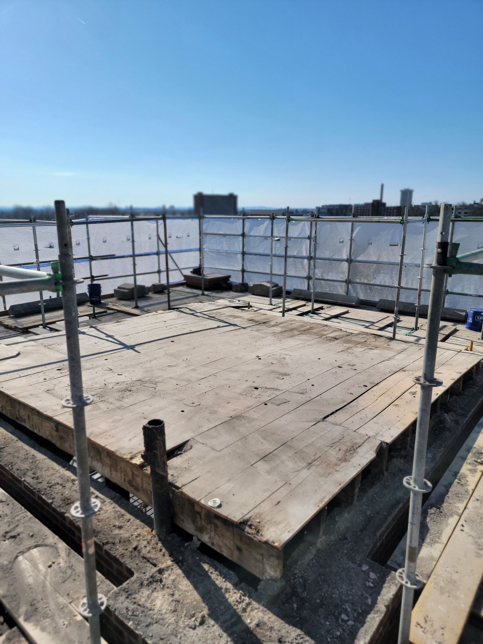 Concrete platform under construction with metal railings, viewed against a bright blue sky.