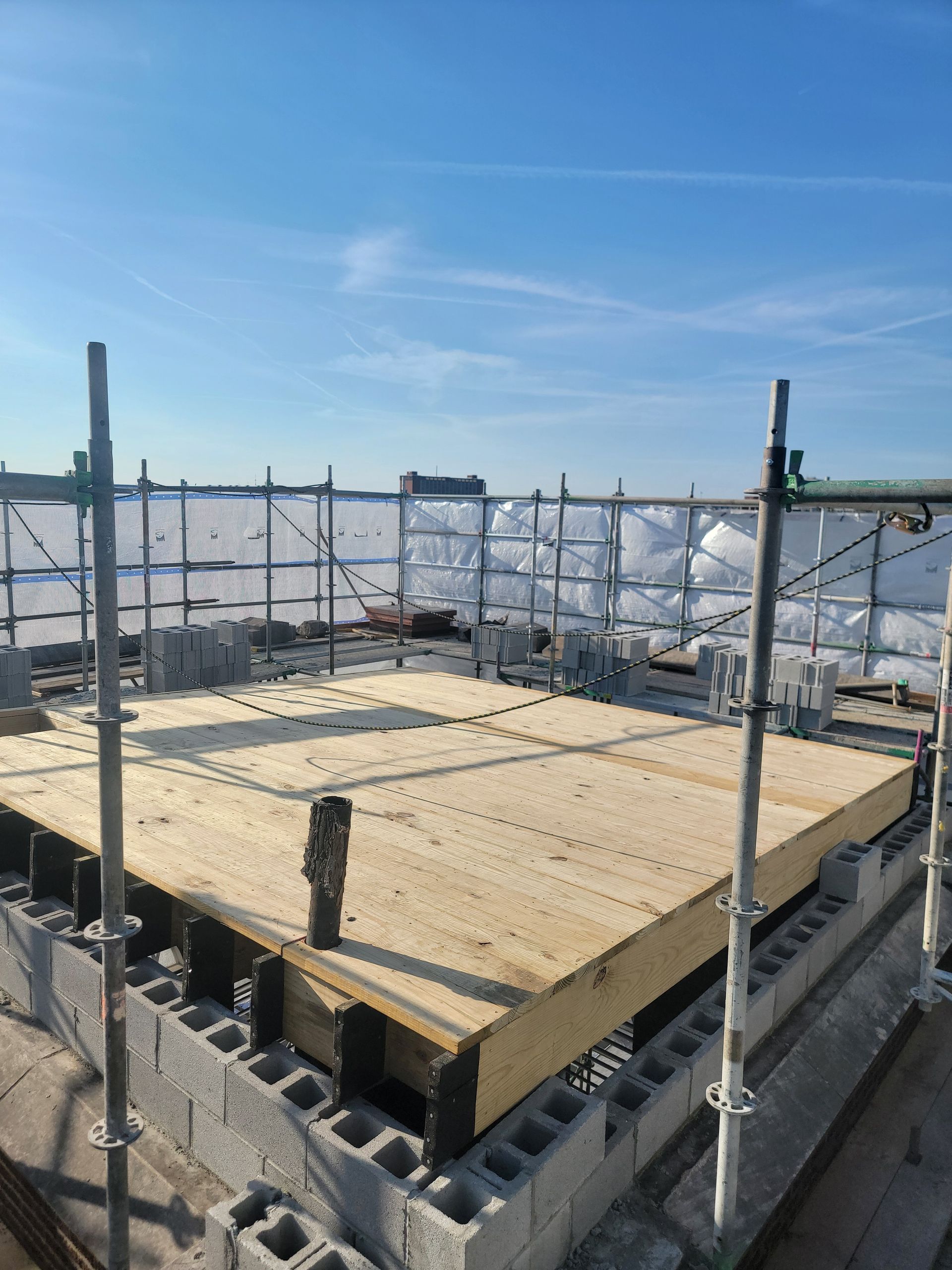 Construction platform with wooden decking and metal scaffolding under a clear blue sky