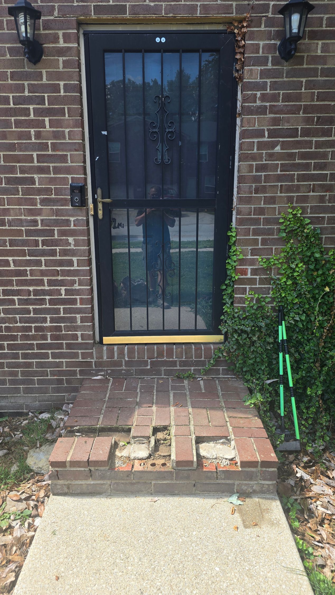 Brick house entry with a black metal security door and small step up from the walkway