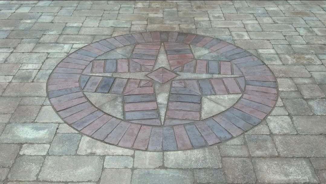 Circular brick compass design set into a paved stone walkway.