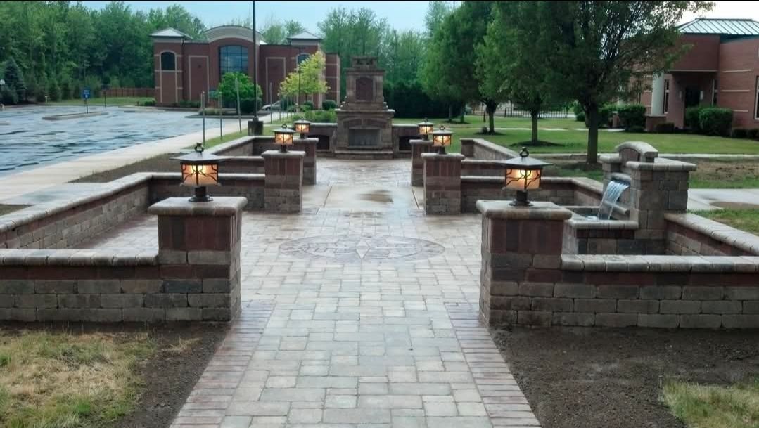 Brick patio with stone benches and planters in a landscaped park garden