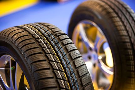 Close-up of two black automotive tires with detailed tread patterns and alloy wheels, conveying precision, durability, and performance.