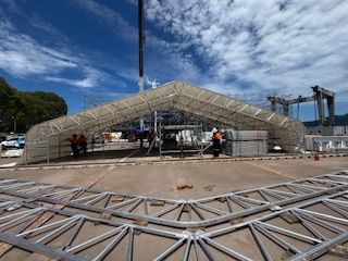 Construction Site With A Partially Built Temporary Structure. Wooden Floors, Metal Framework, And A White Canvas Roof Are Visible — T & T Scaffolding in Gordonvale, QLD