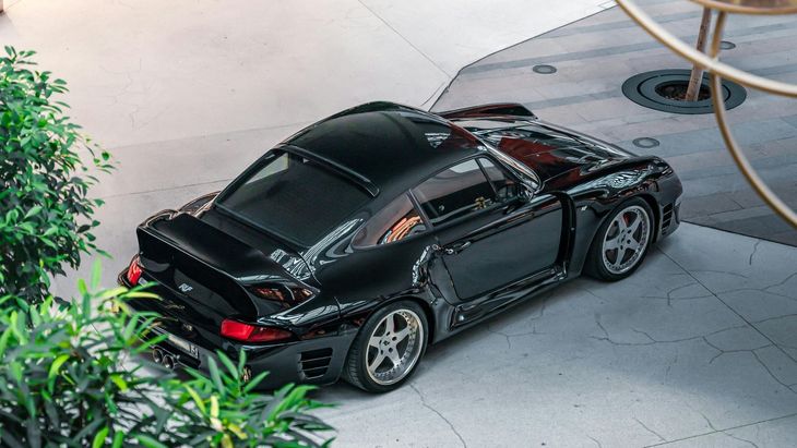 A silver porsche 911 carrera s is parked on a showroom floor.