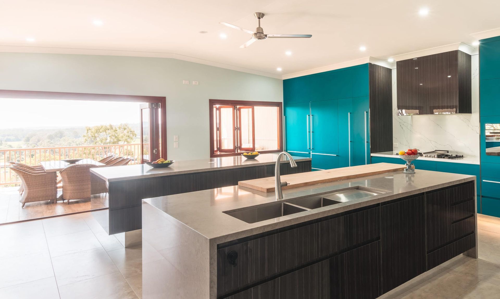 Modern Kitchen With Teal Cabinetry, Dual Islands, and Open Access to an Outdoor Dining Area — Akyrah Kitchens in Gympie, QLD