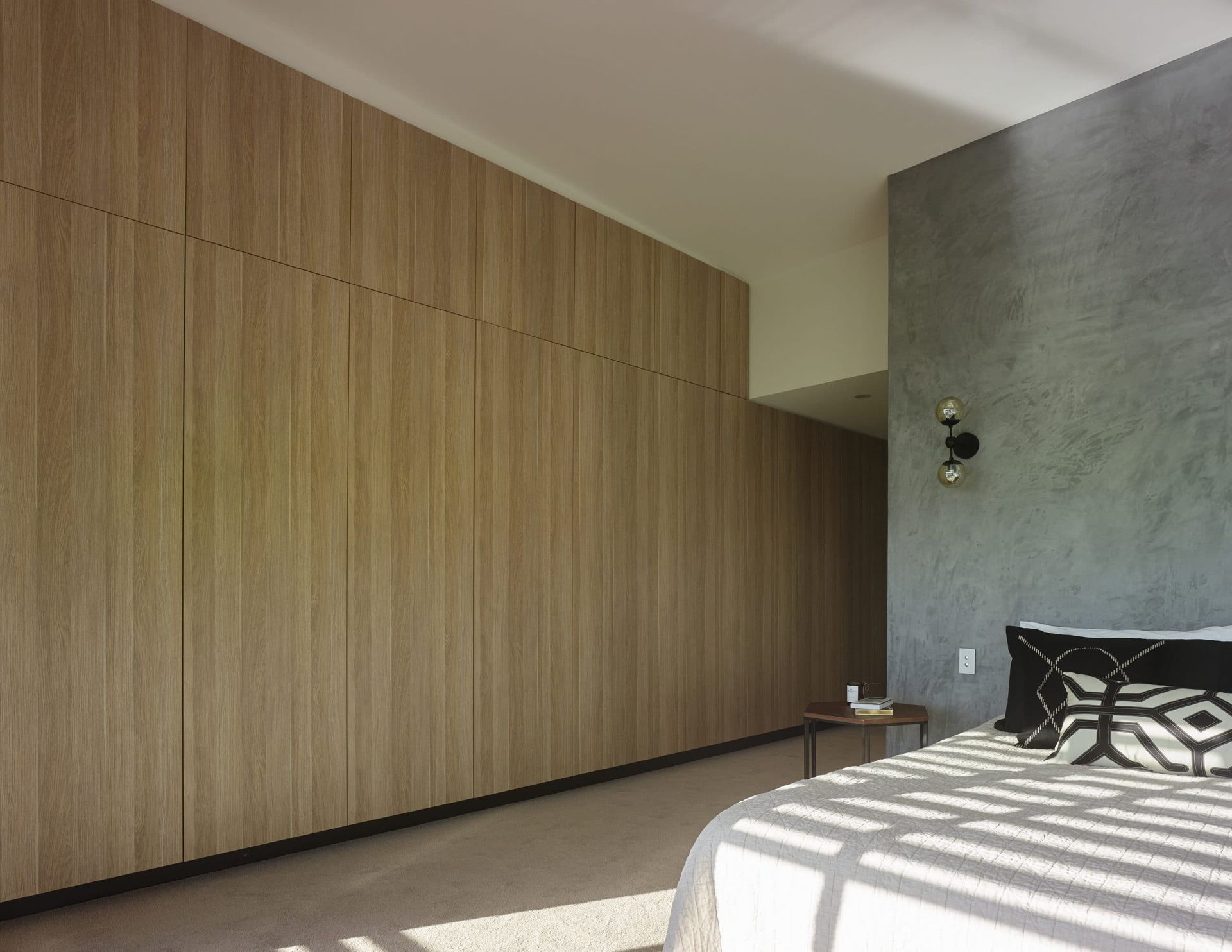 Bedroom With Light Wood Closet Doors on One Wall and a Textured Gray Wall Beside the Bed — Akyrah Kitchens in Gympie, QLD