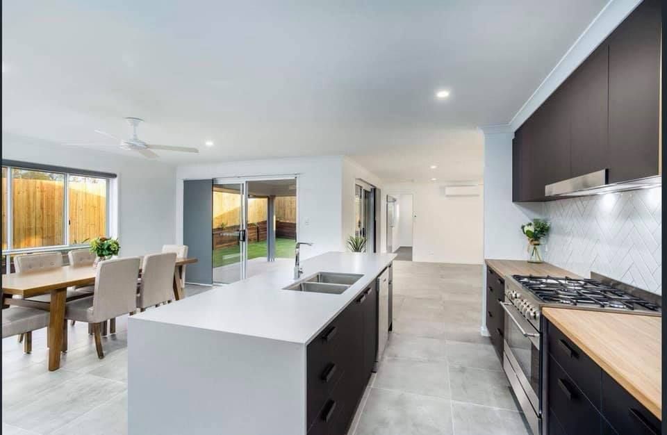 Modern Kitchen With Island, Dark Cabinets, Stainless Steel Appliances, and Dining Area — Akyrah Kitchens in Gympie, QLD