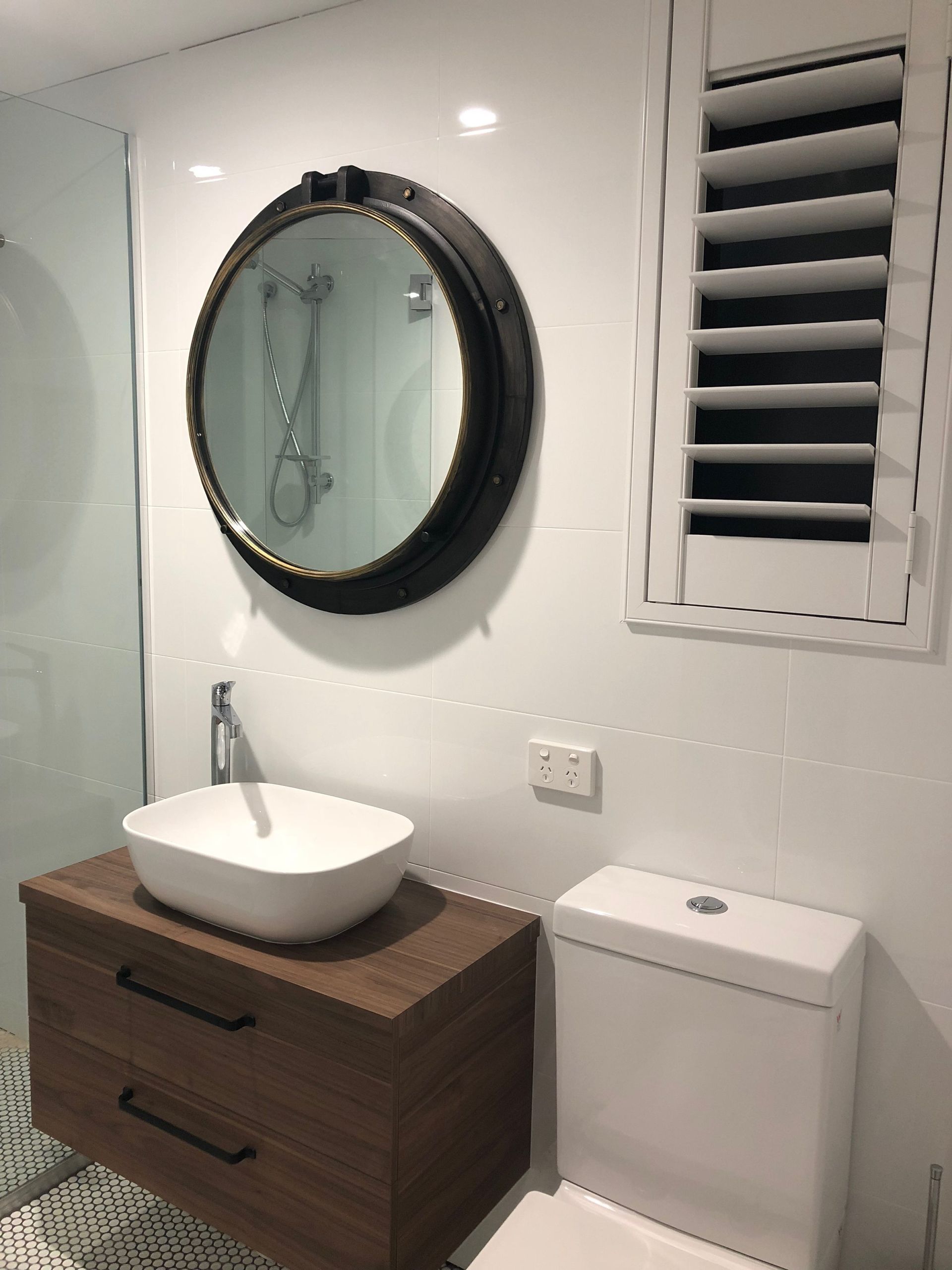 Bathroom With Round Mirror, Vessel Sink on Wooden Cabinet, and White Toilet — Akyrah Kitchens in Gympie, QLD