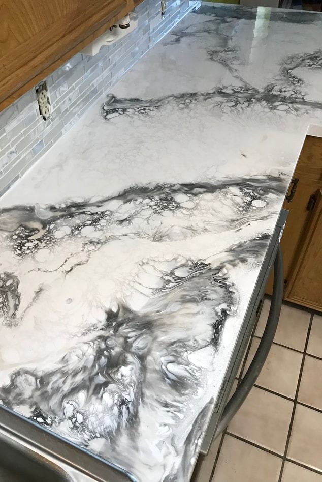 Marble-look white countertop with gray veining beside a tiled floor and wooden cabinets