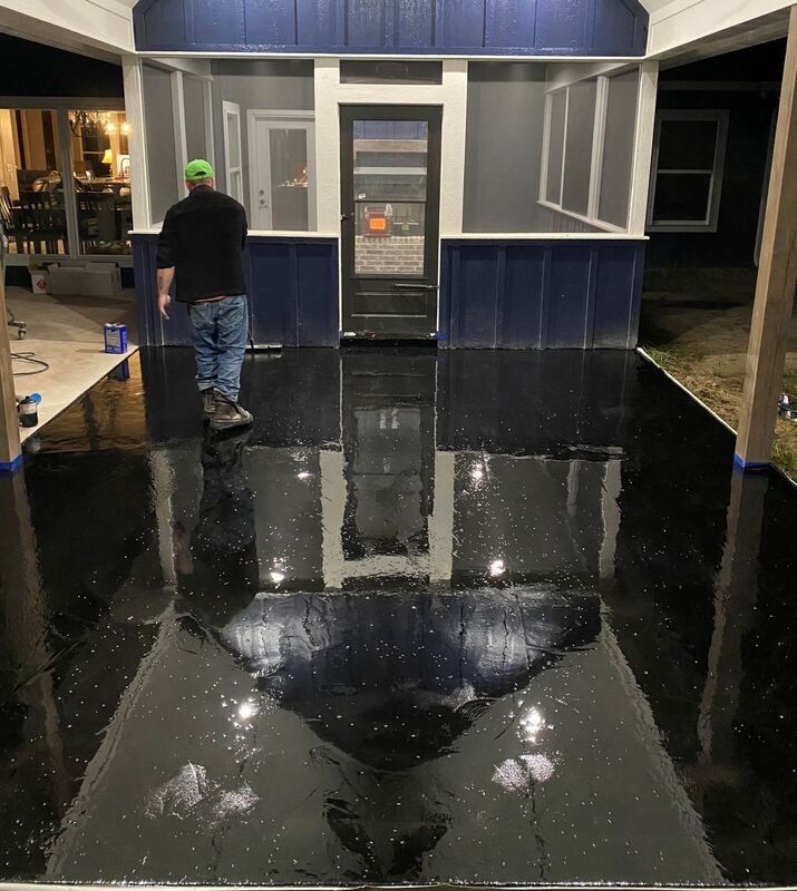 Nighttime porch with a glossy black floor and a person standing near the front door.
