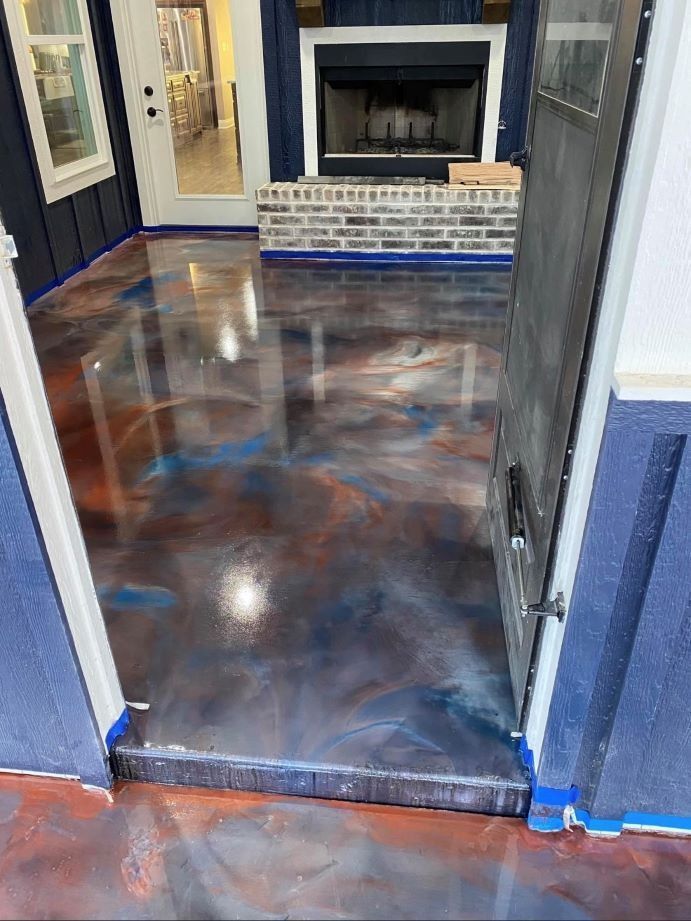 Polished marbled floor in a doorway leading to a room with a fireplace and blue trim