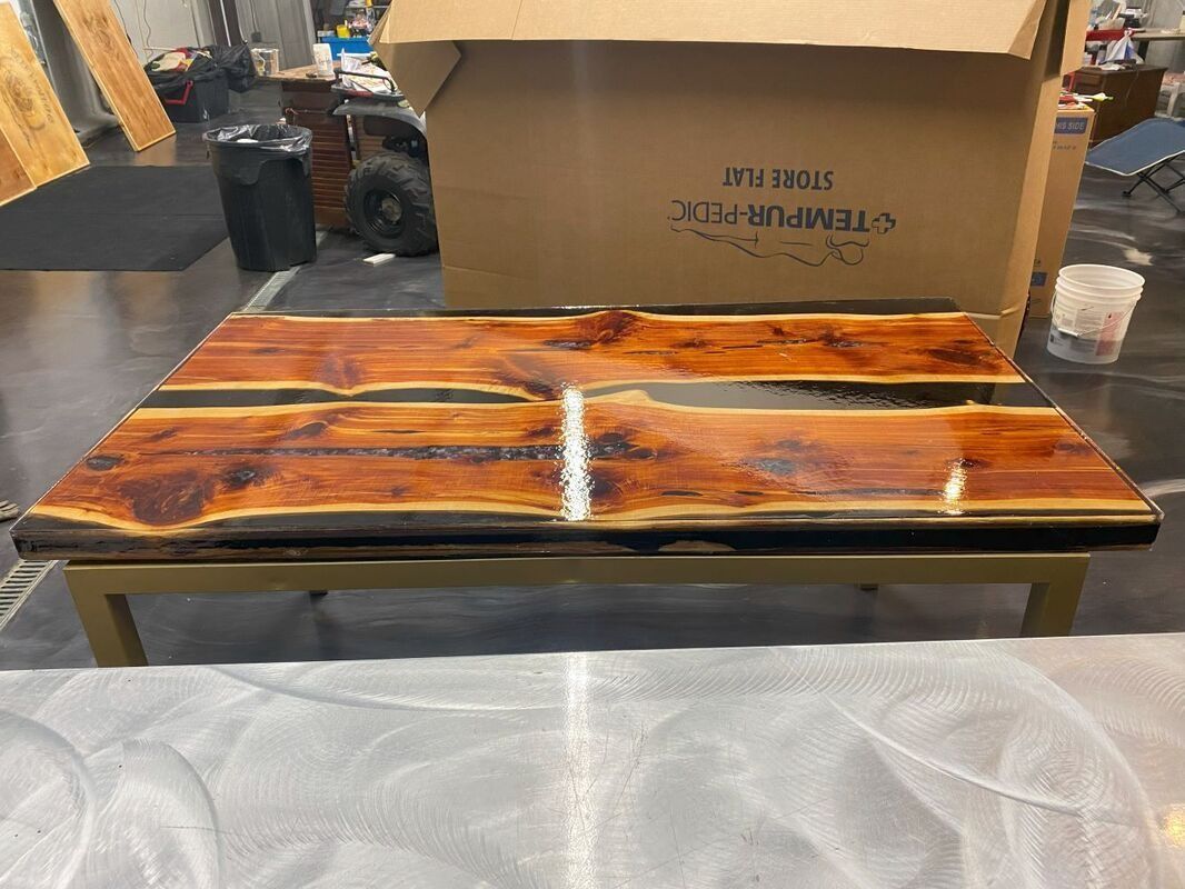 Handmade resin wood serving tray with orange, black, and white swirls on a table in a workshop setting
