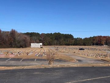 Winter cemetery with many grave markers, a small white sign, and trees under a clear blue sky
