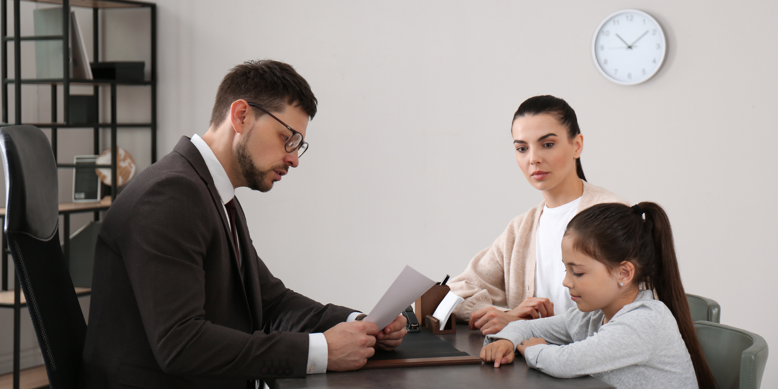 Three coworkers in a meeting reviewing documents at a table in a bright office