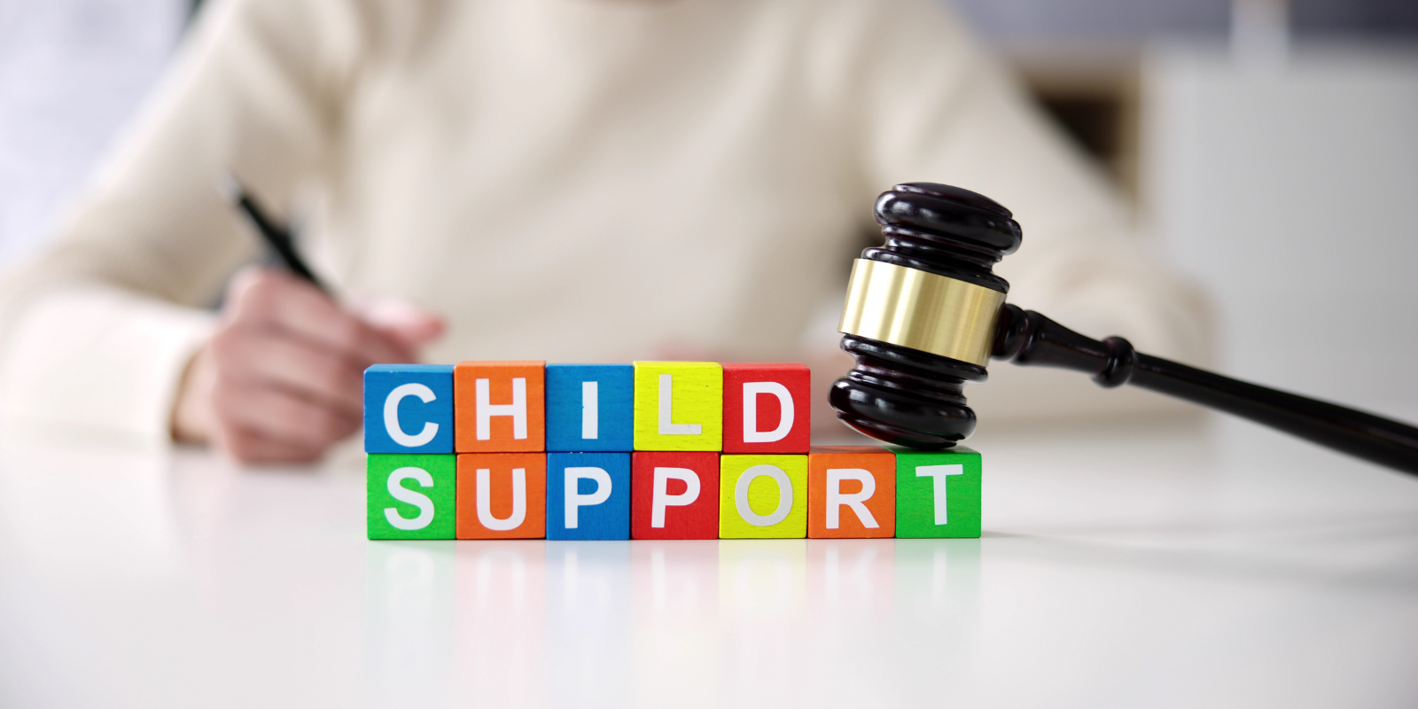 Colorful CHILD SUPPORT blocks beside a judge’s gavel on a desk