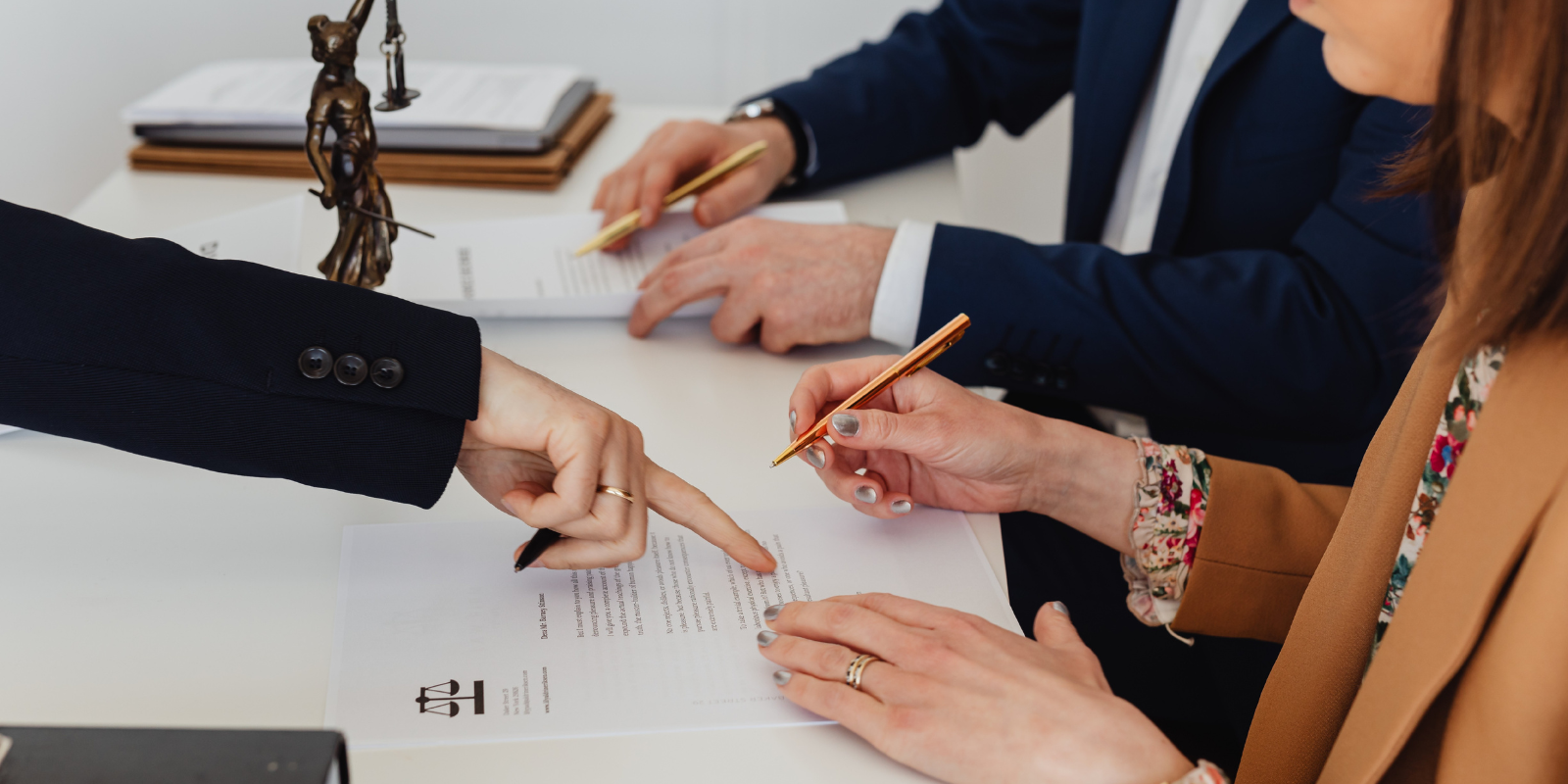 Hands exchanging and signing divorce modification at a lawyer meeting table with pens and papers.