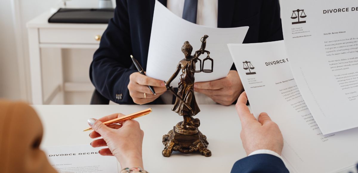 Business meeting with contract documents and a Lady Justice statue on a desk