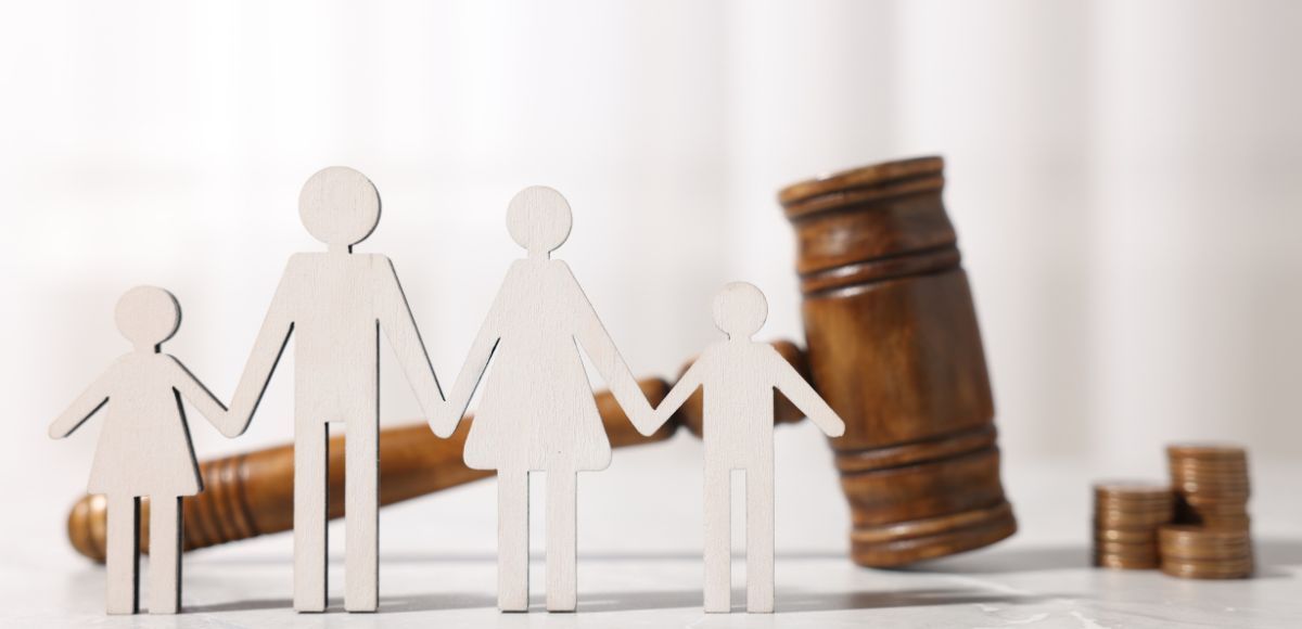 Paper family cutouts beside a judge’s gavel and coins, symbolizing family law or divorce settlement