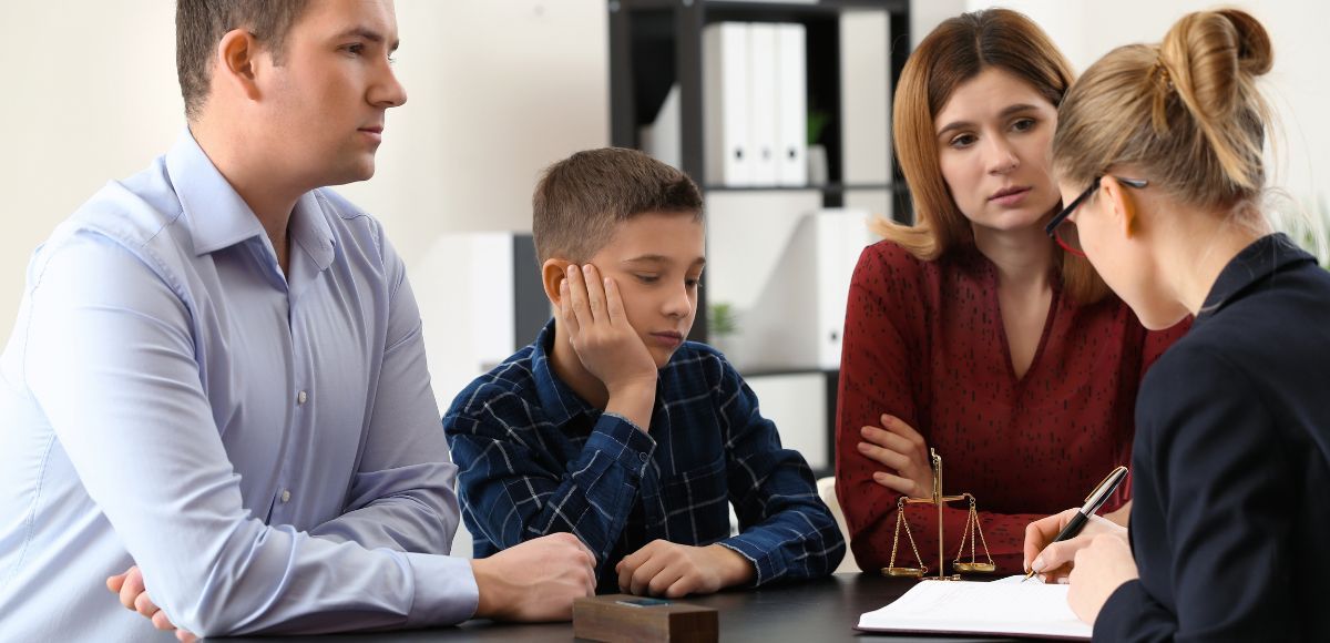 Family in a counseling session, seated around a table, talking with a therapist in an office