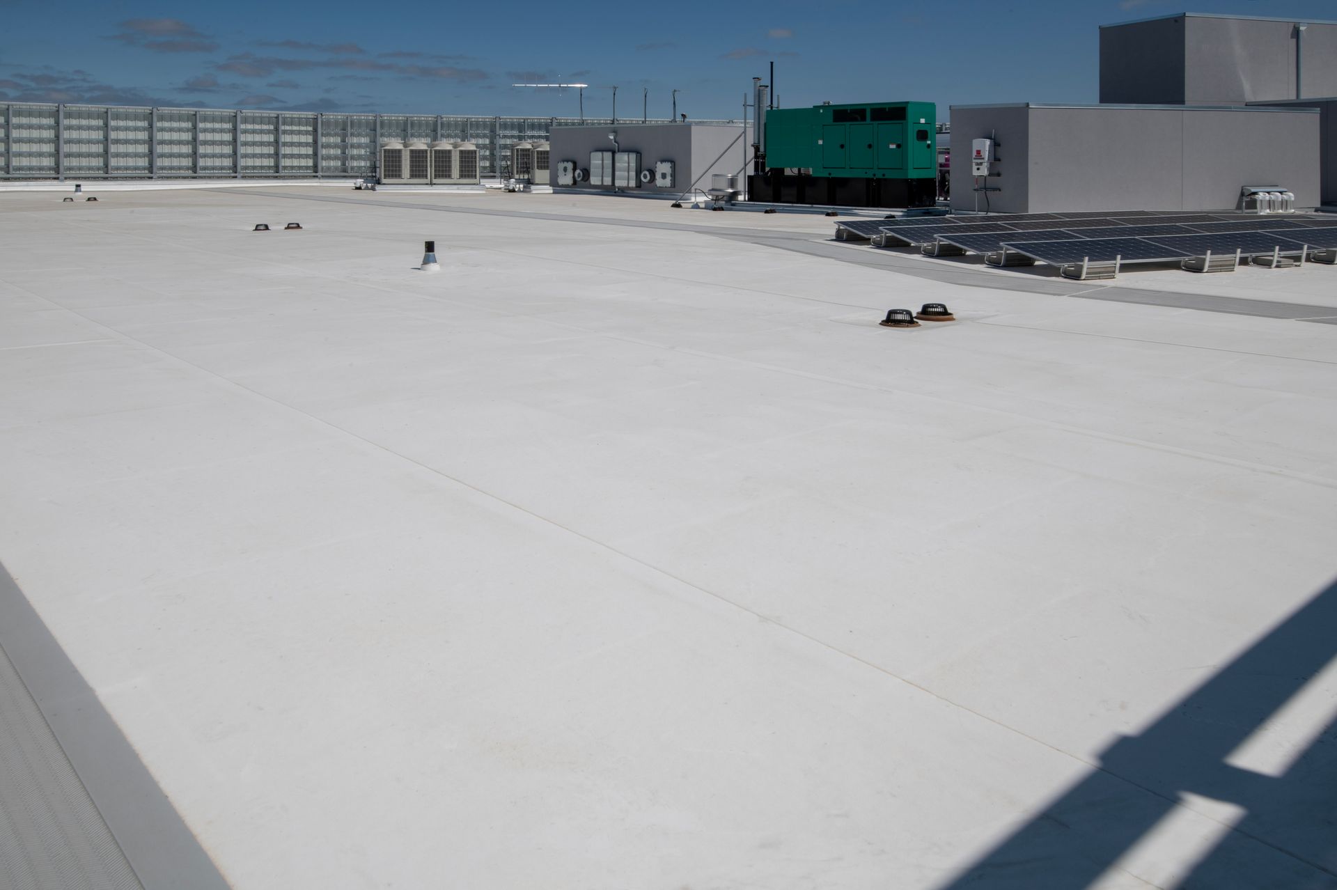 Flat, black roof with several vents. Trees in the background.
