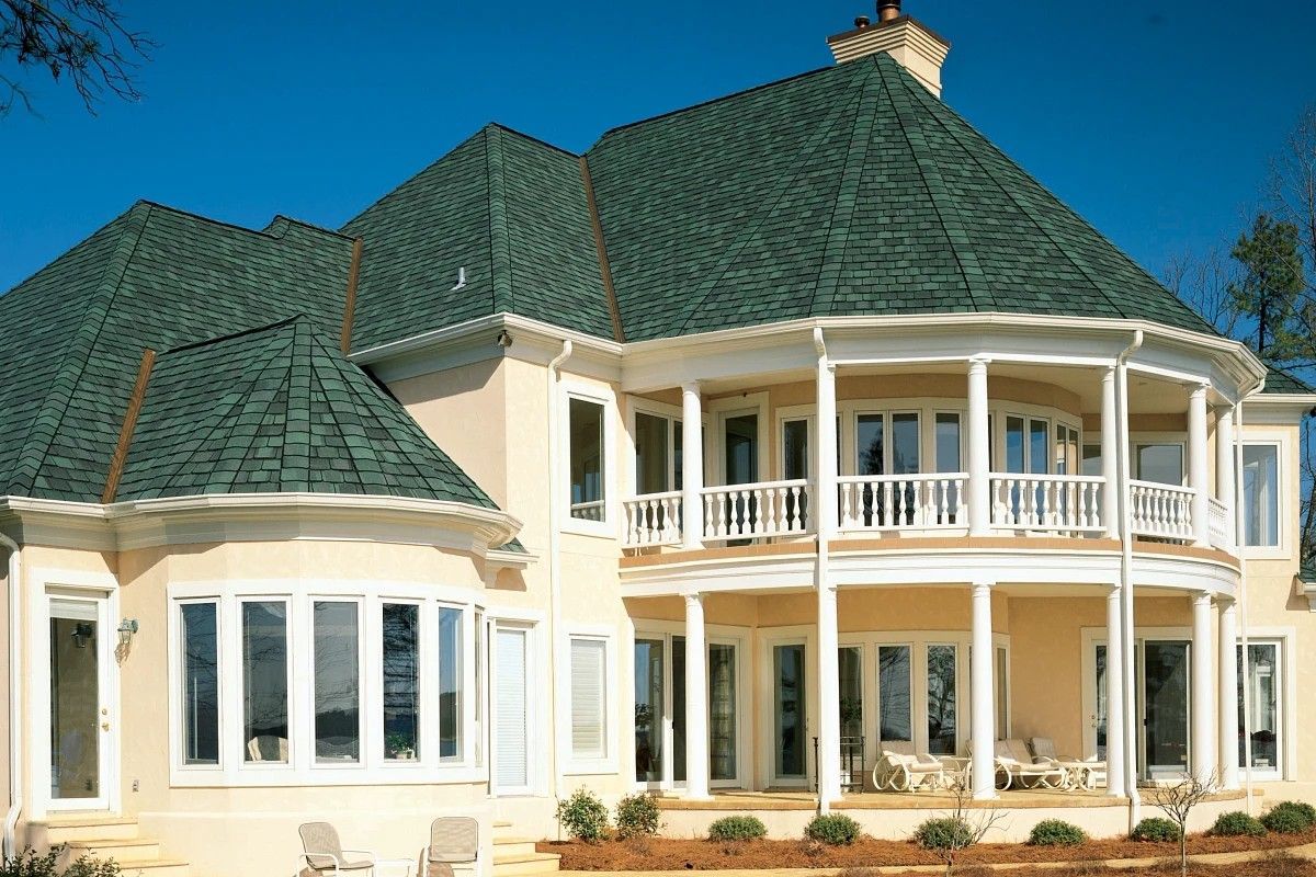 Overhead view of a house with brown shingle roof on green grass.