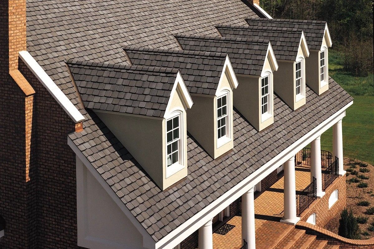 Scale model house with gray shingled roof, white dormer windows, and front porch columns
