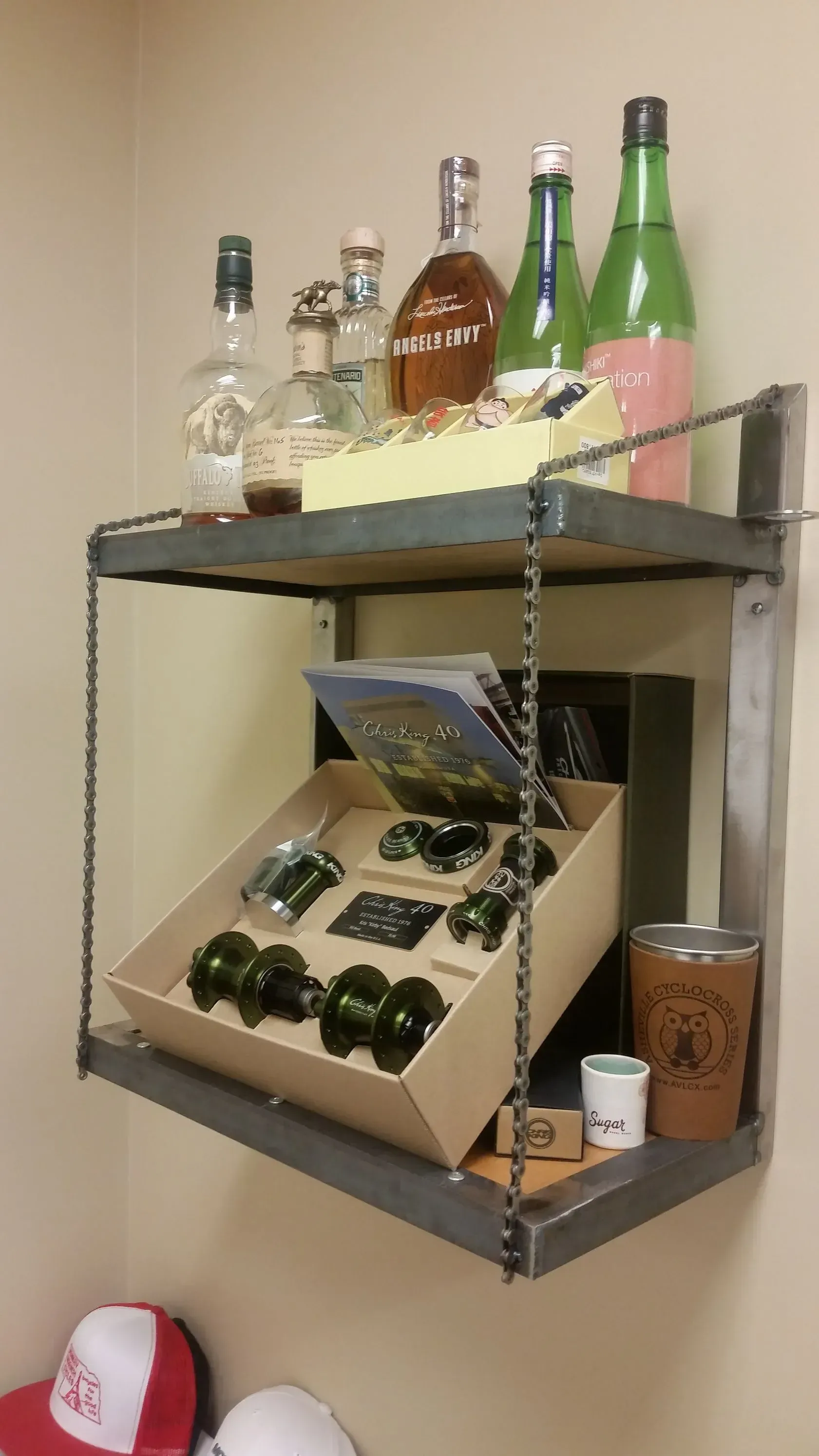 Wall shelf with assorted liquor bottles, a wine rack, and a cup in a room corner.