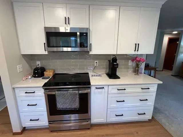 Modern kitchen with white cabinets, stainless steel stove and microwave, and countertop coffee maker