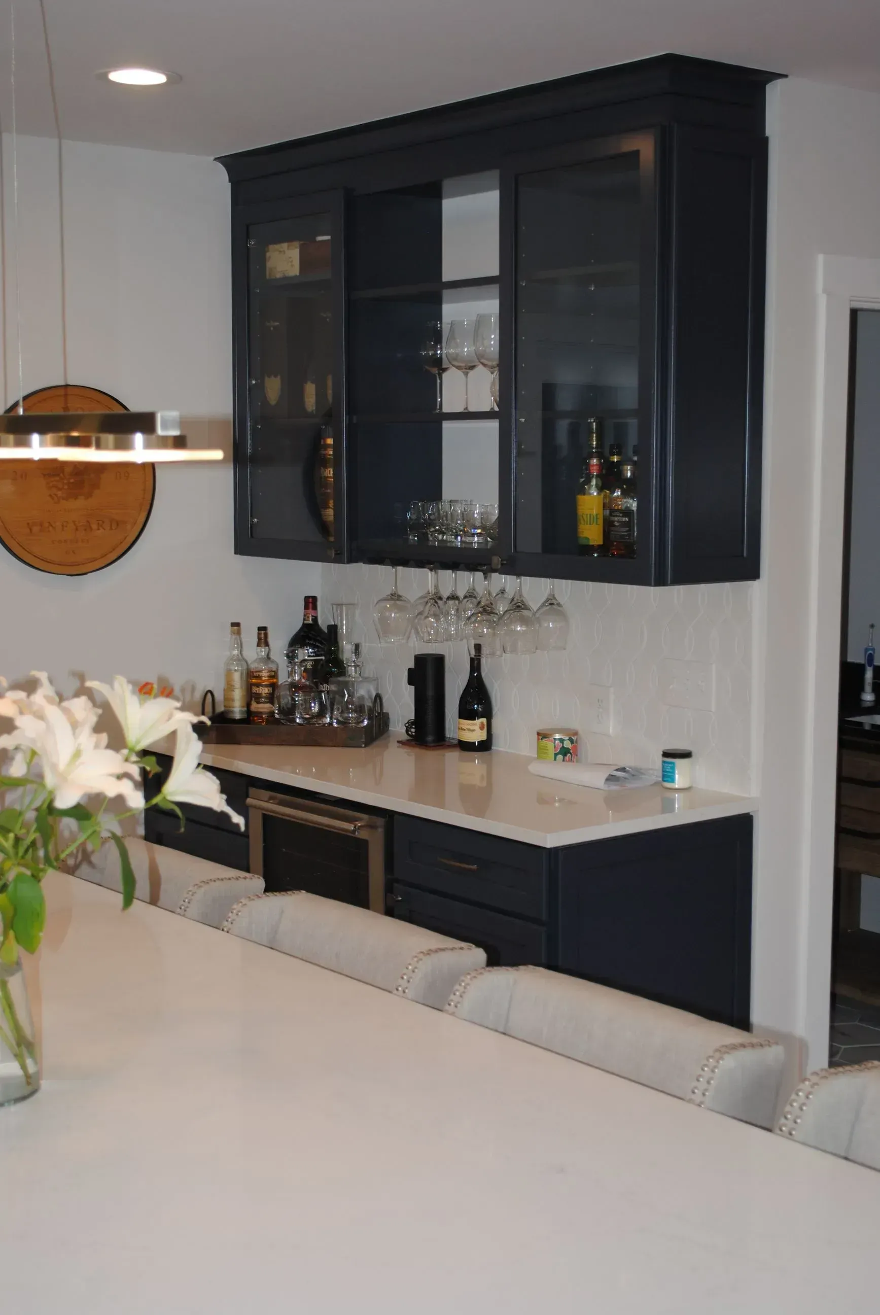 Modern kitchen with dark cabinets, white countertops, and a large island in the foreground