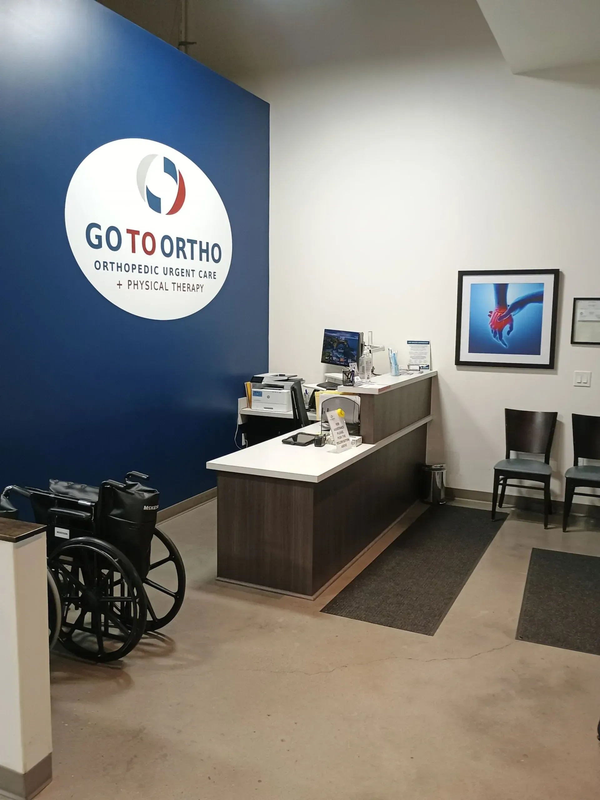 Dental office reception area with blue wall, wheelchair, desk, and waiting chairs.