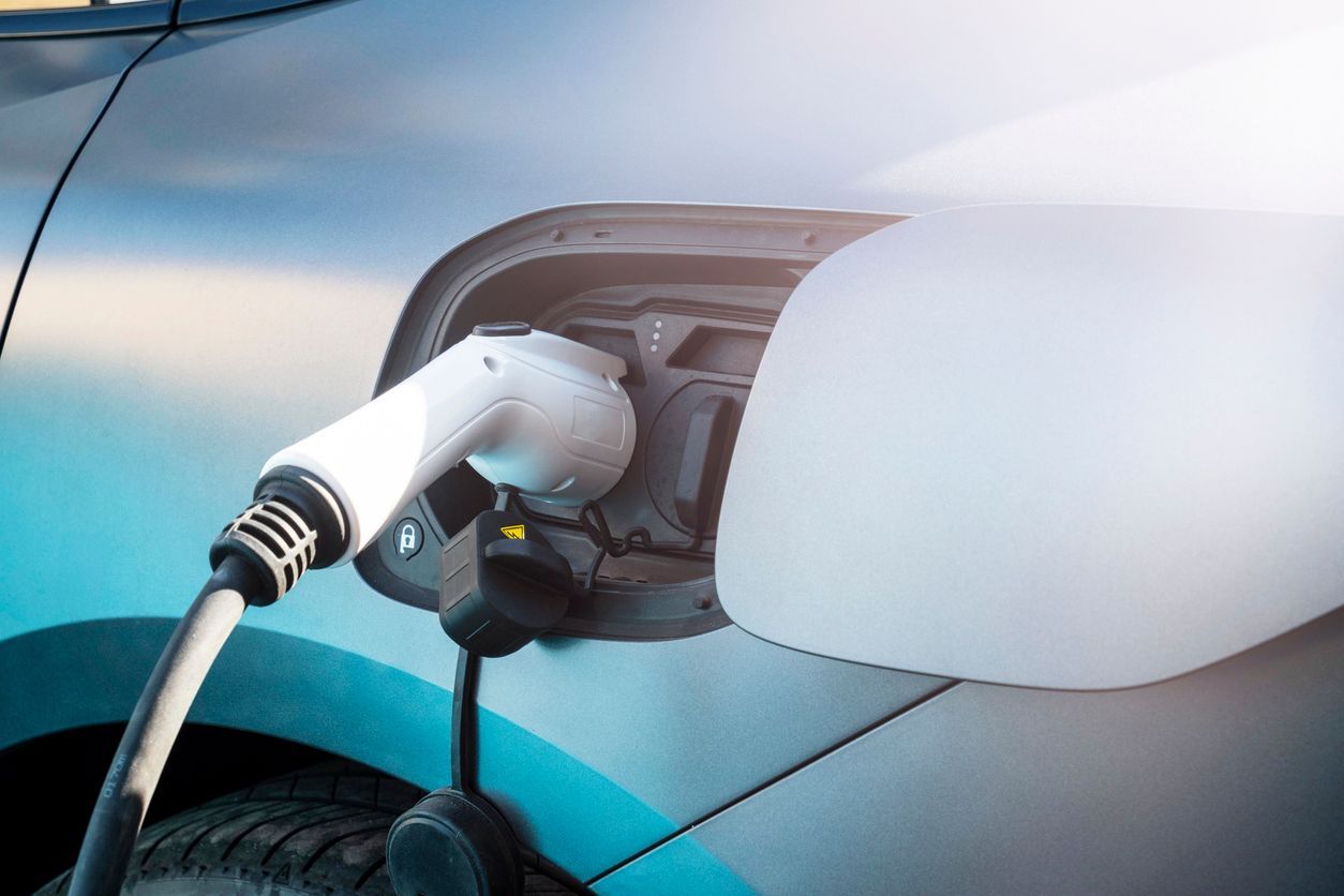 Electric car charging plug connected to a blue vehicle’s charging port