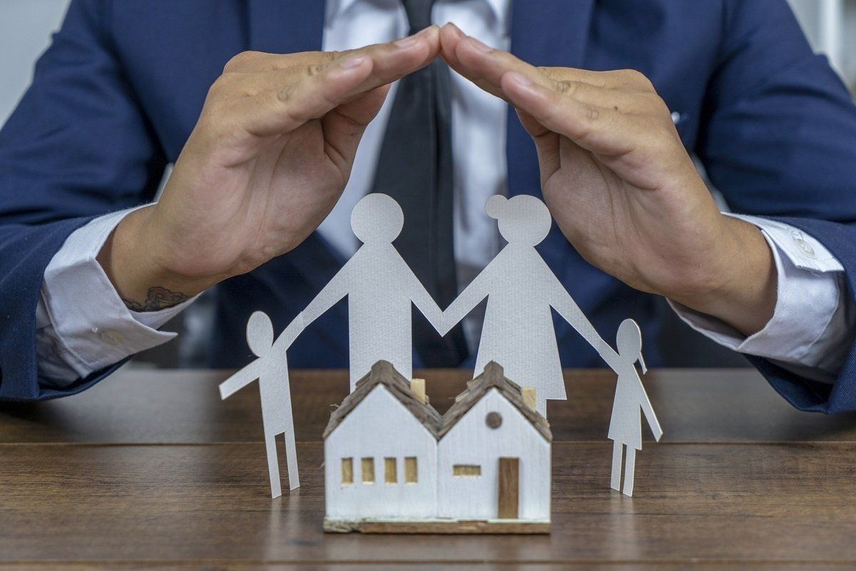Hands covering family paper dolls — Macon, GA — Heart Of Georgia Insurance Brokers