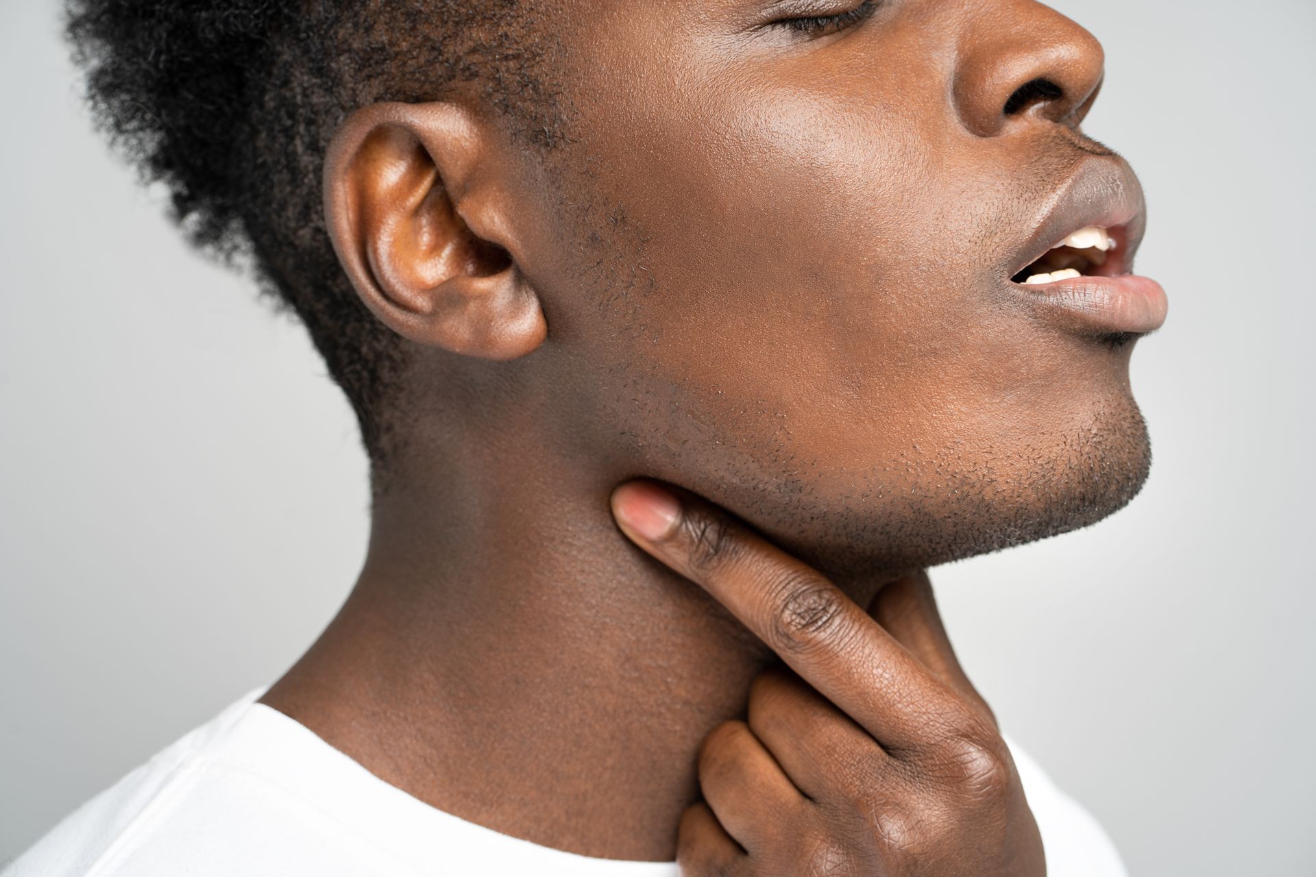 A close up of a man holding his neck with his hand.