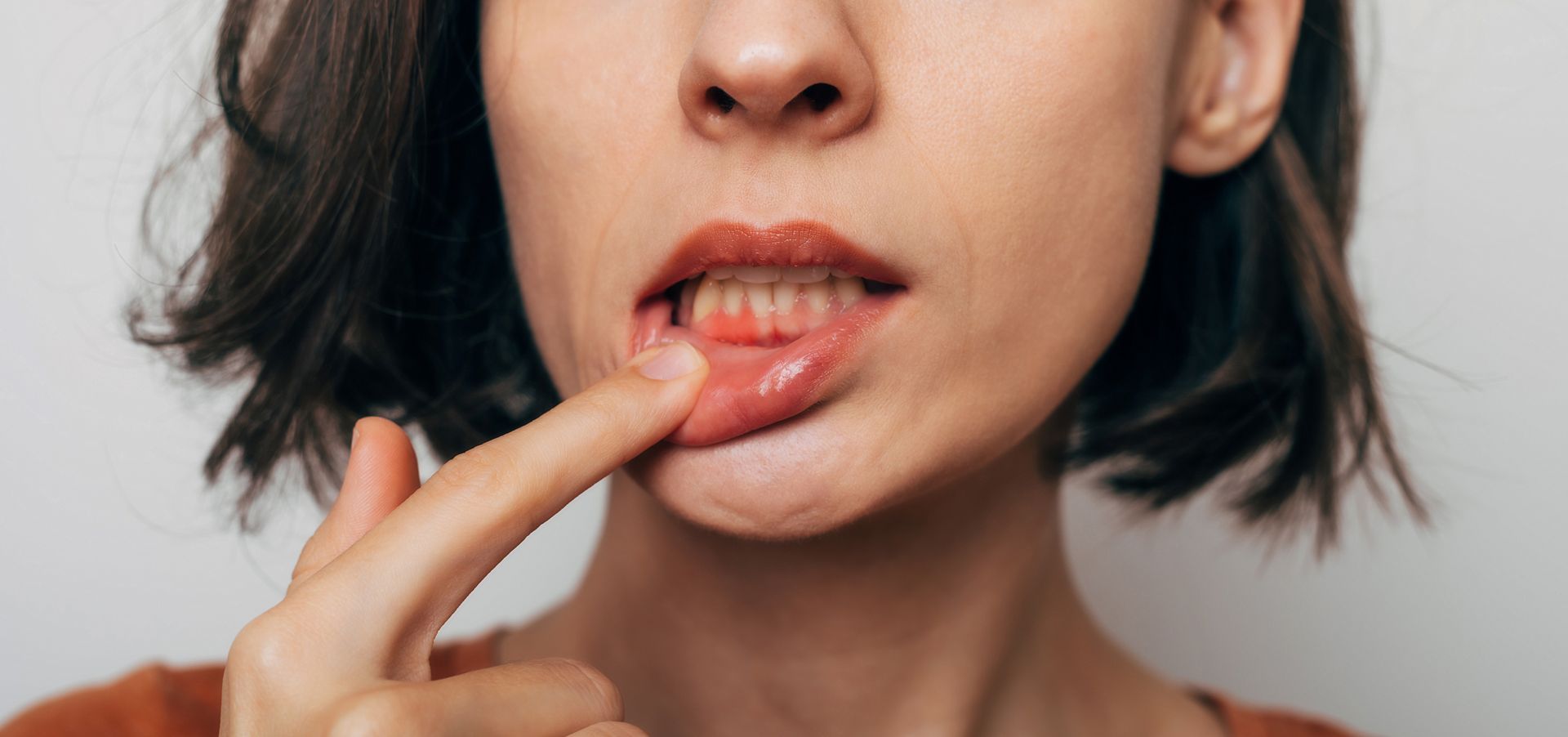 A woman is holding her finger to her mouth.