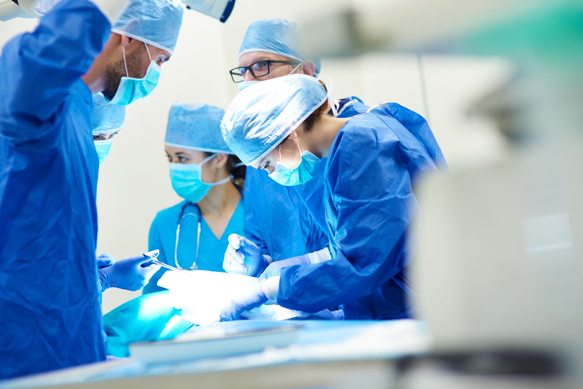 A group of surgeons are operating on a patient in an operating room.