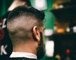 Man with dark hair and a faded haircut, facing right, in a barber shop.