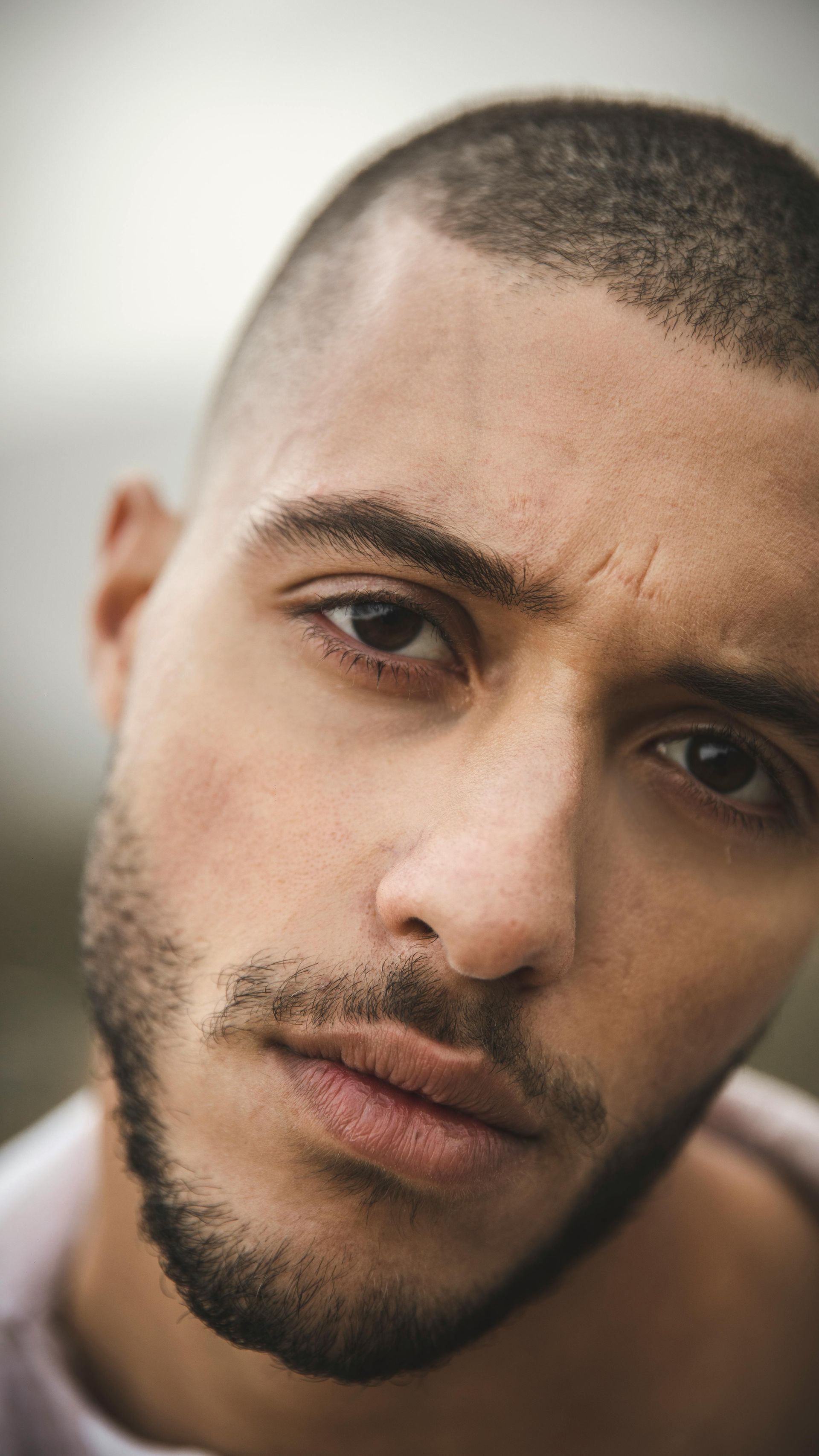 Close-up of a man with dark hair and a beard, looking intensely at the camera.