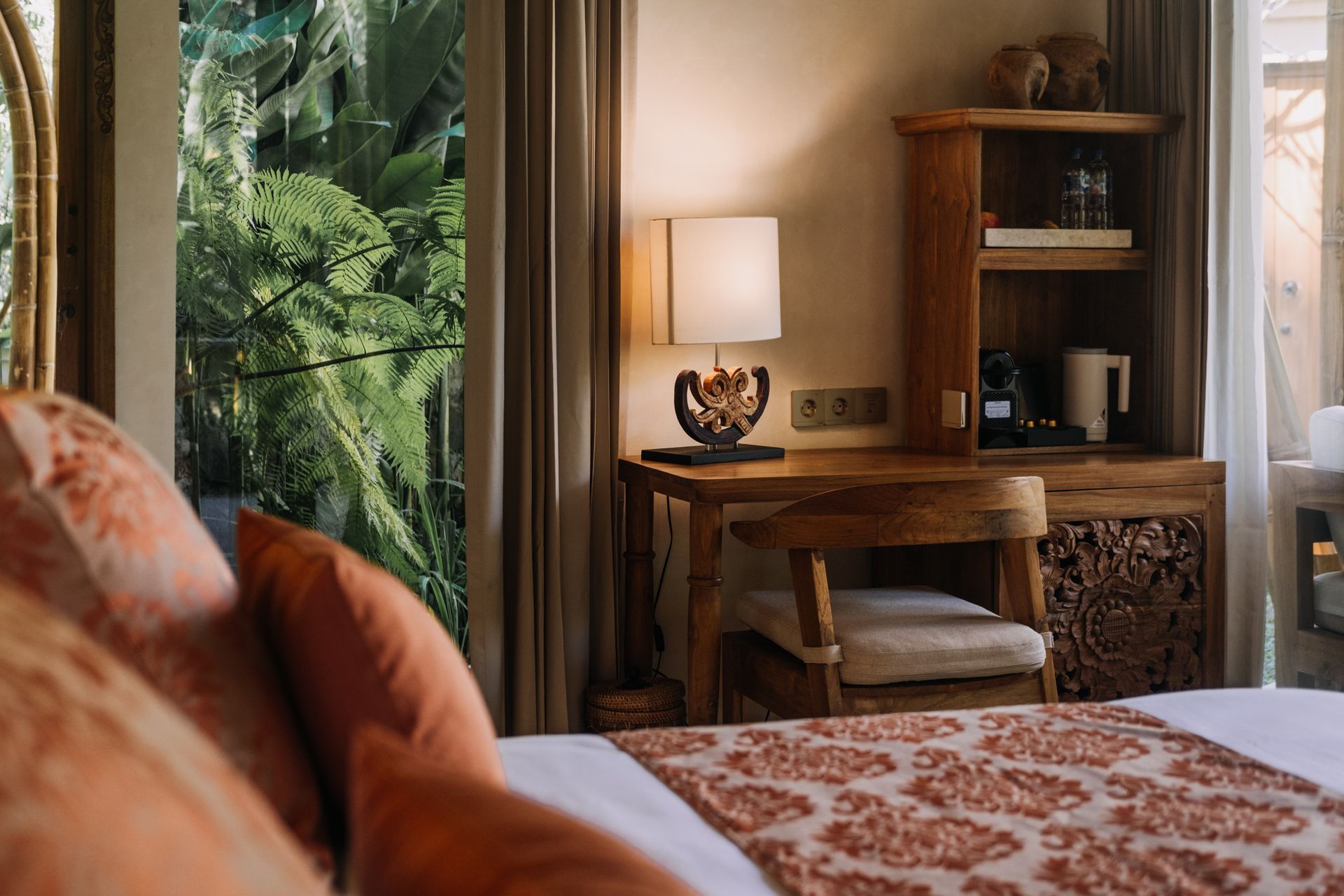 Hotel room with two beds, brick walls, desk, TV, and decorative plants.
