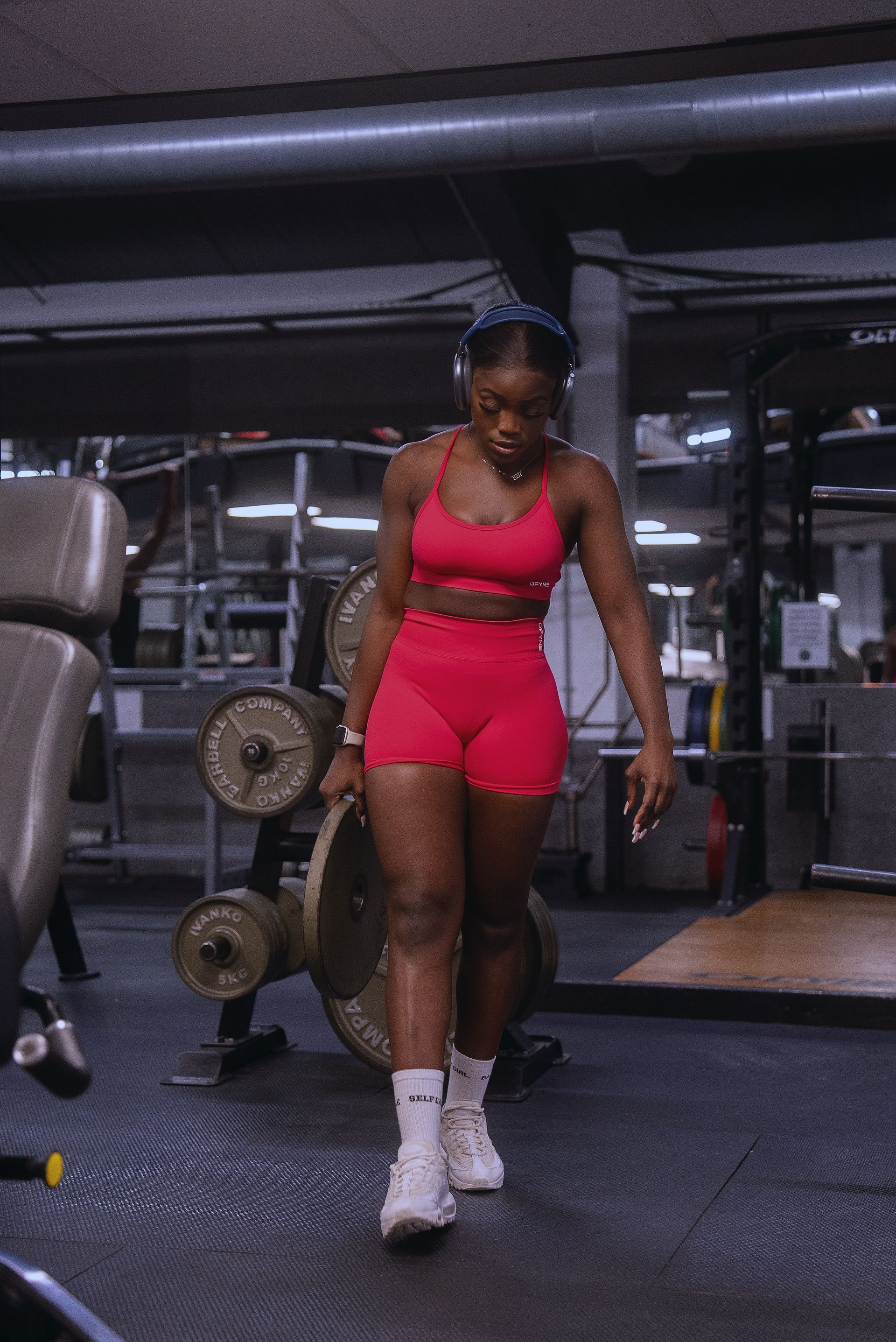 Nonye is standing in a gym holding a barbell.
