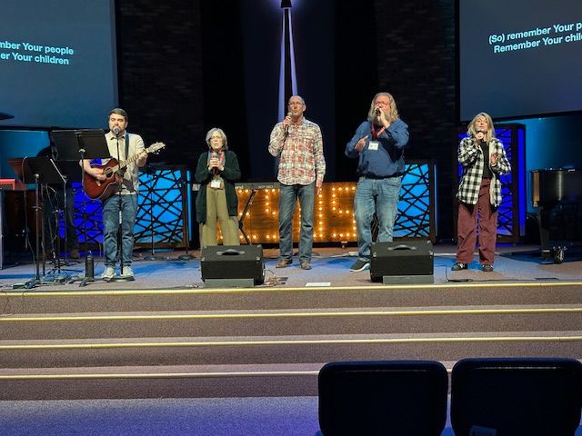A group of people are standing in a church with their hands in the air.