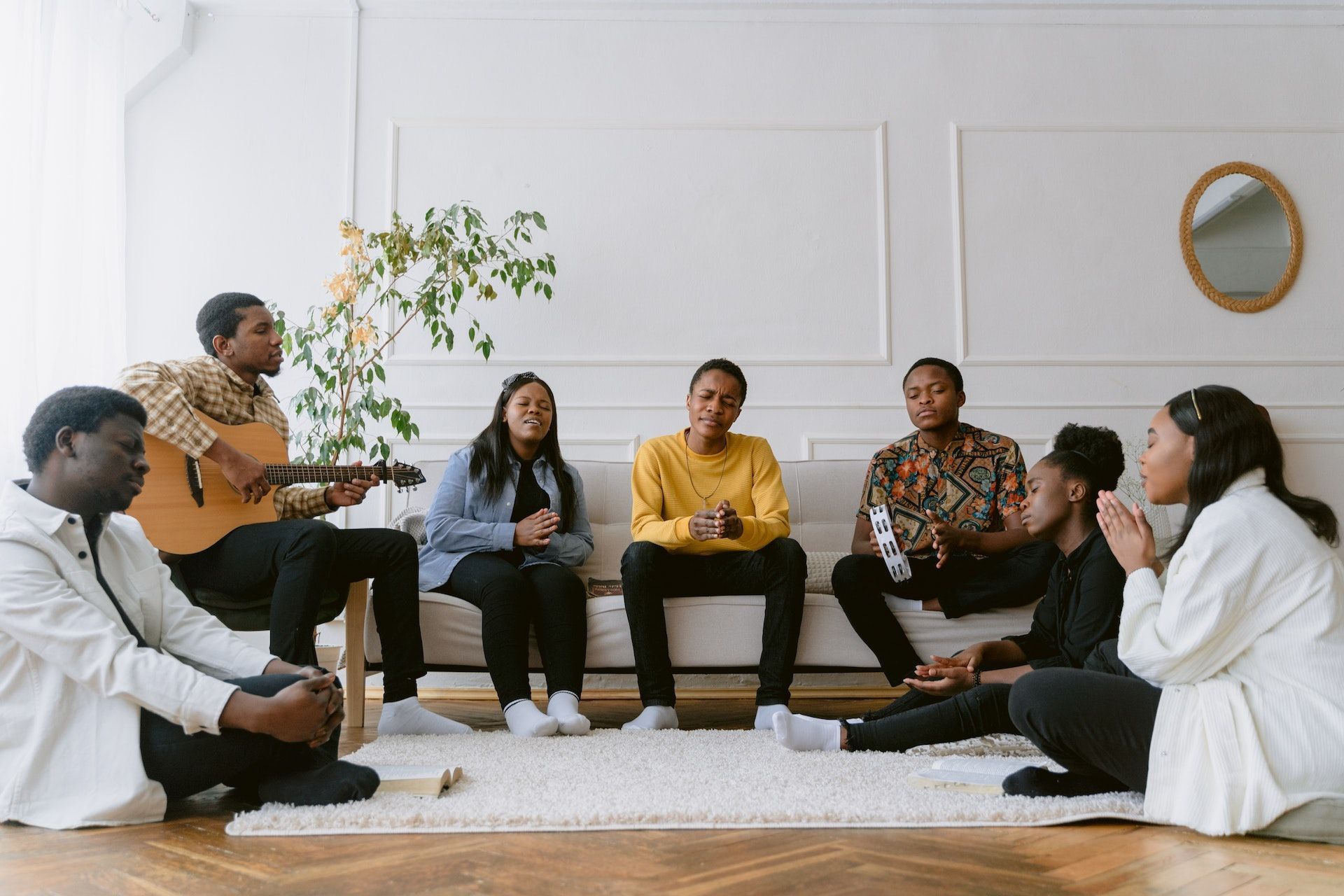 A group of people are sitting around a couch in a living room.