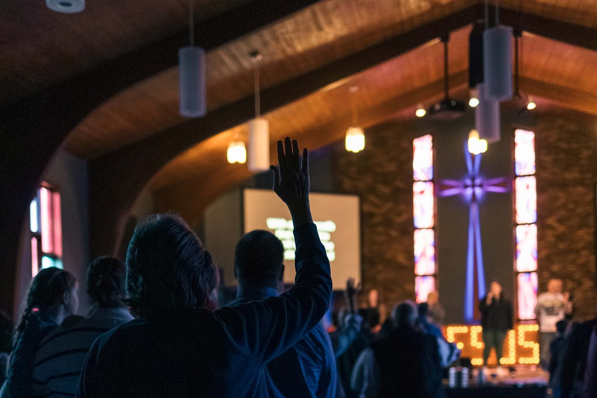 A group of people are raising their hands in a church.