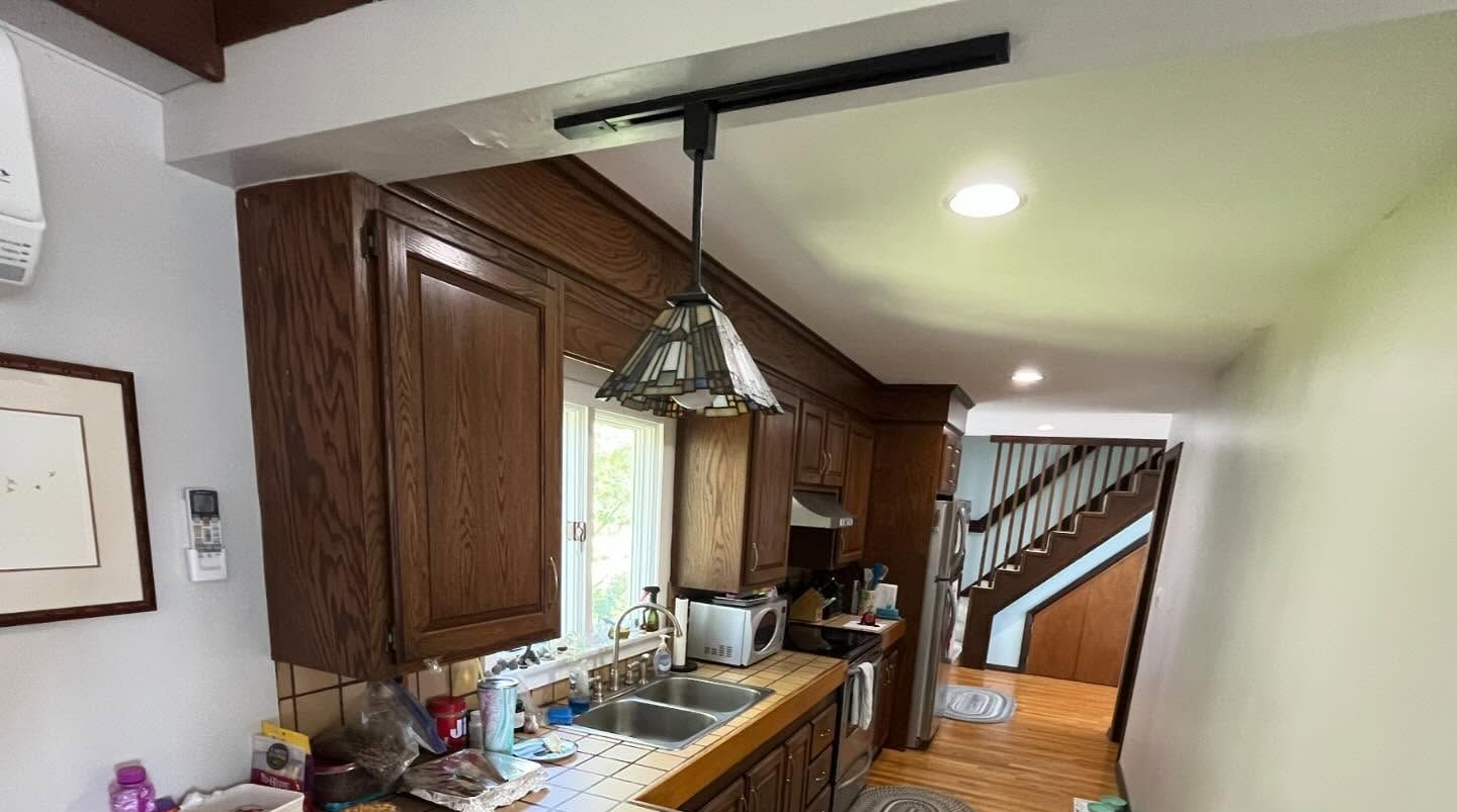 Kitchen with dark wood cabinets, a sink, and a hanging light fixture. A staircase is visible in the background.