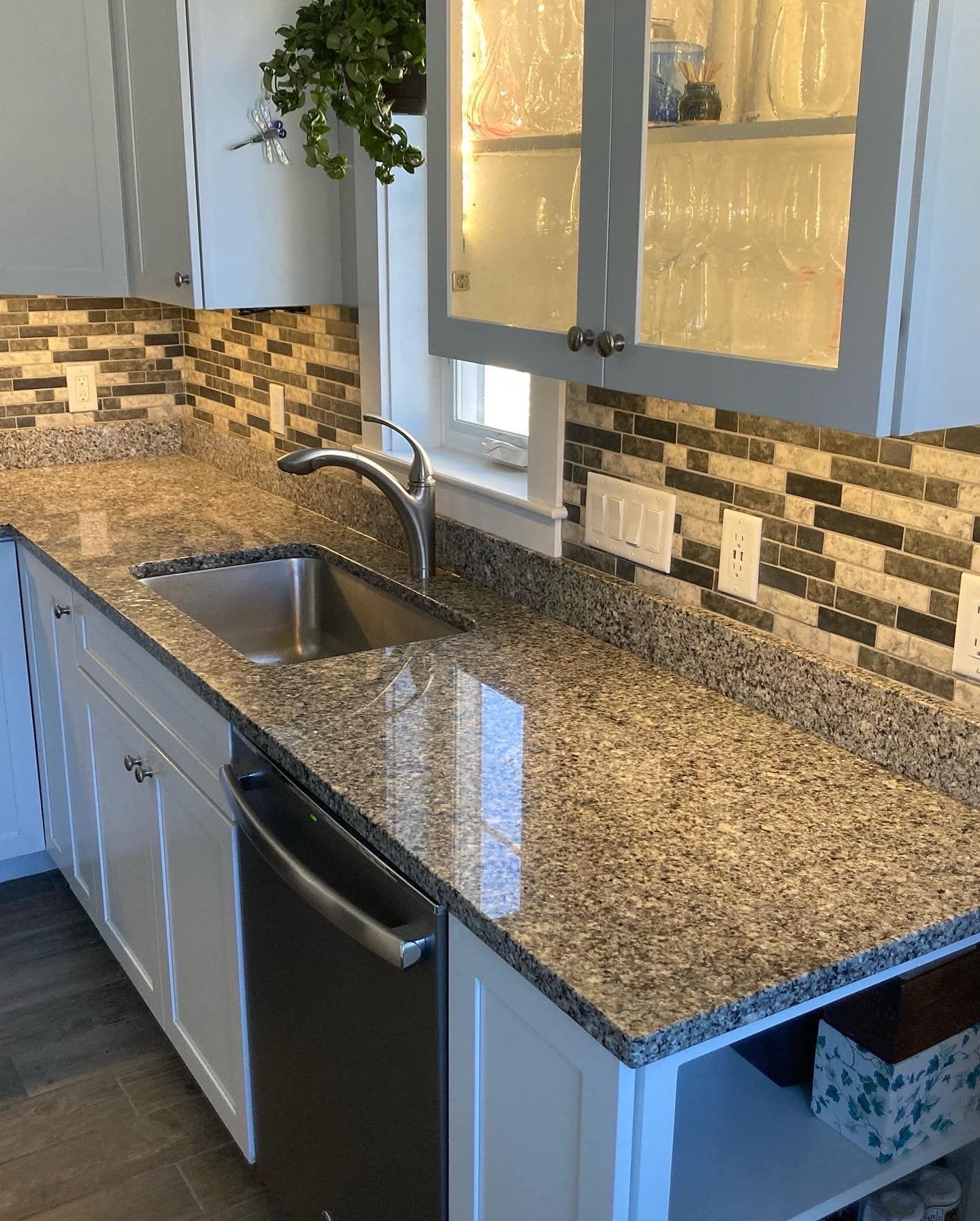 Kitchen with granite countertops, stainless steel sink, backsplash, and gray cabinets.